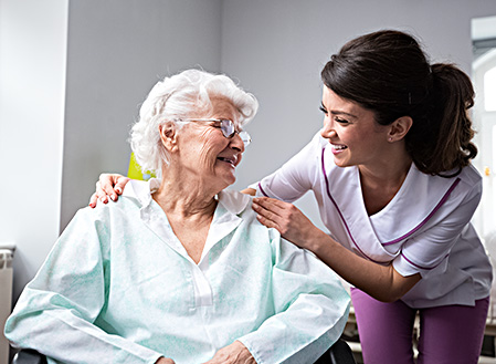 Elderly patient and nurse smiling at each other