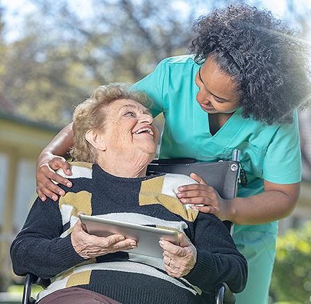 Senior patient in wheelchair smiling at nurse