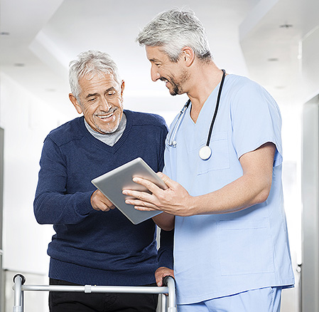 Physiotherapist Showing Reports On Tablet Computer To Senior Man