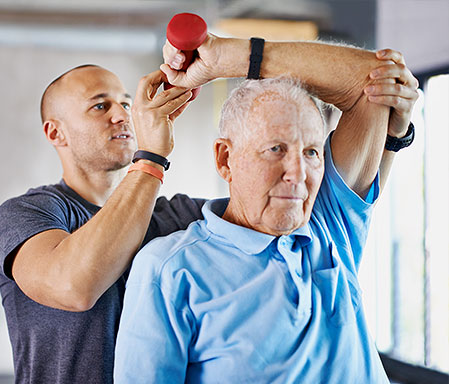 elderly and physical therapist exercising with weights