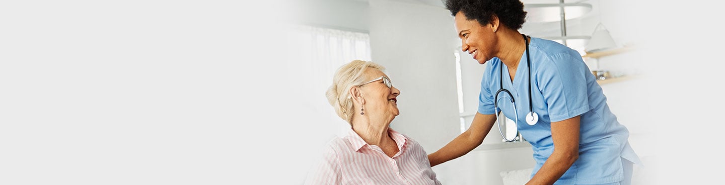 senior patient and nurse smiling at each other