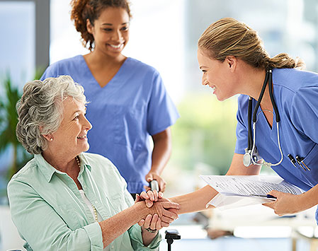 senior shaking hands with nurse staff