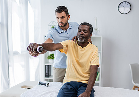 physical therapist spotting patient with weight training